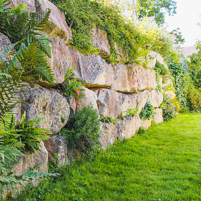 Große Natursteinmauer und Zaun